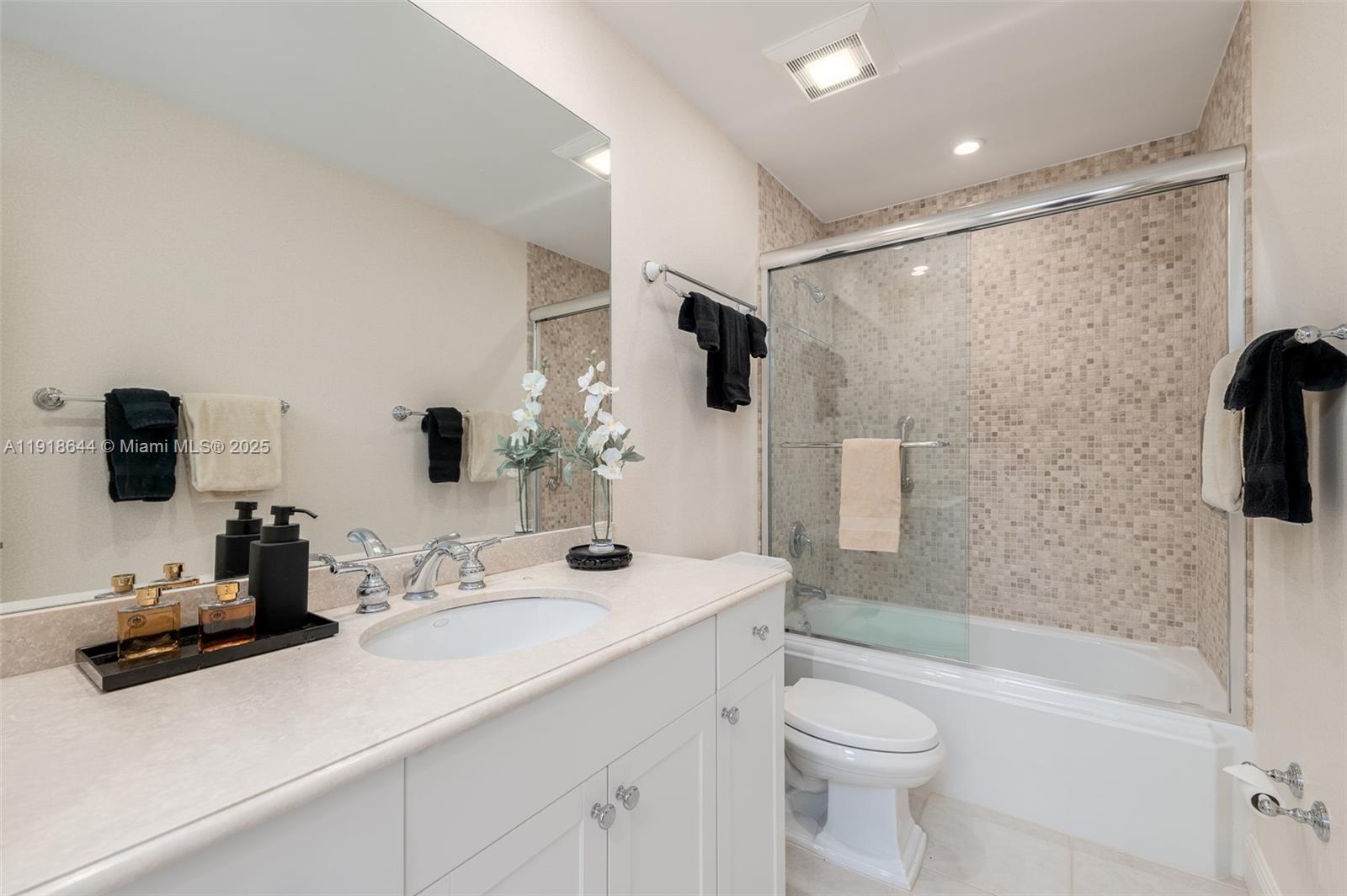 11609 Southeast Florida Avenue Hobe Sound, FL 33455 - Photo 26 of 31 a bathroom with a sink a toilet a mirror a bathtub and shower