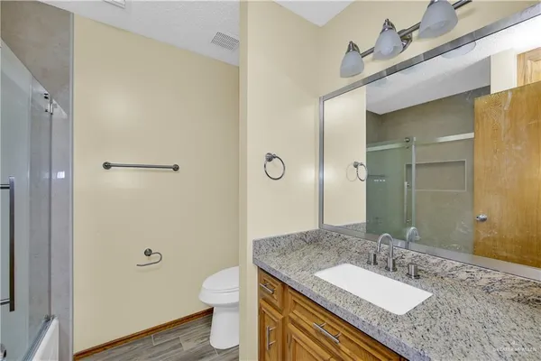 a bathroom with a granite countertop sink toilet and shower