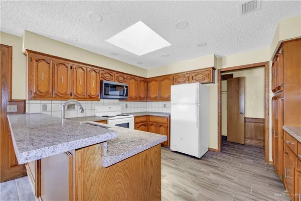 a kitchen with stainless steel appliances granite countertop a refrigerator stove microwave sink and cabinets