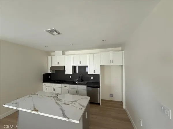a kitchen with granite countertop white cabinets and black appliances