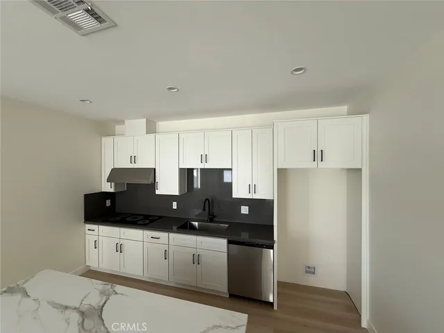 a kitchen with granite countertop white cabinets and black appliances