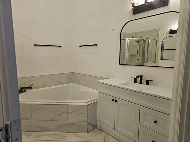 a bathroom with a tub a sink and mirror