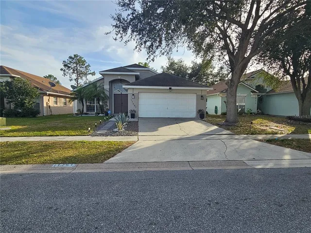 a view of a house with a yard and a large tree