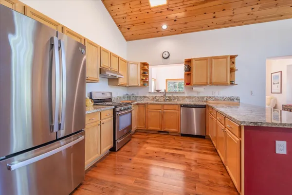 a kitchen with stainless steel appliances granite countertop a stove top oven a sink and dishwasher with wooden floor