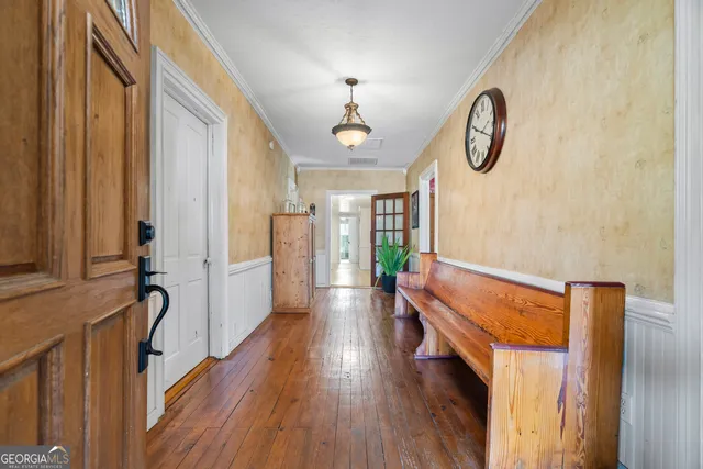 a view of a hallway with wooden floor and a bathroom view