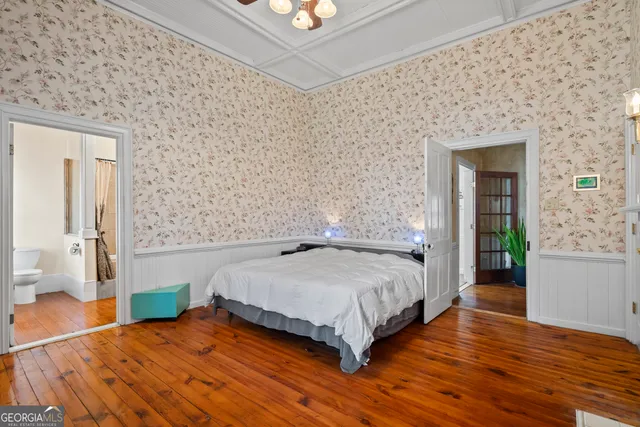 a bedroom with a bed and dresser with wooden floor