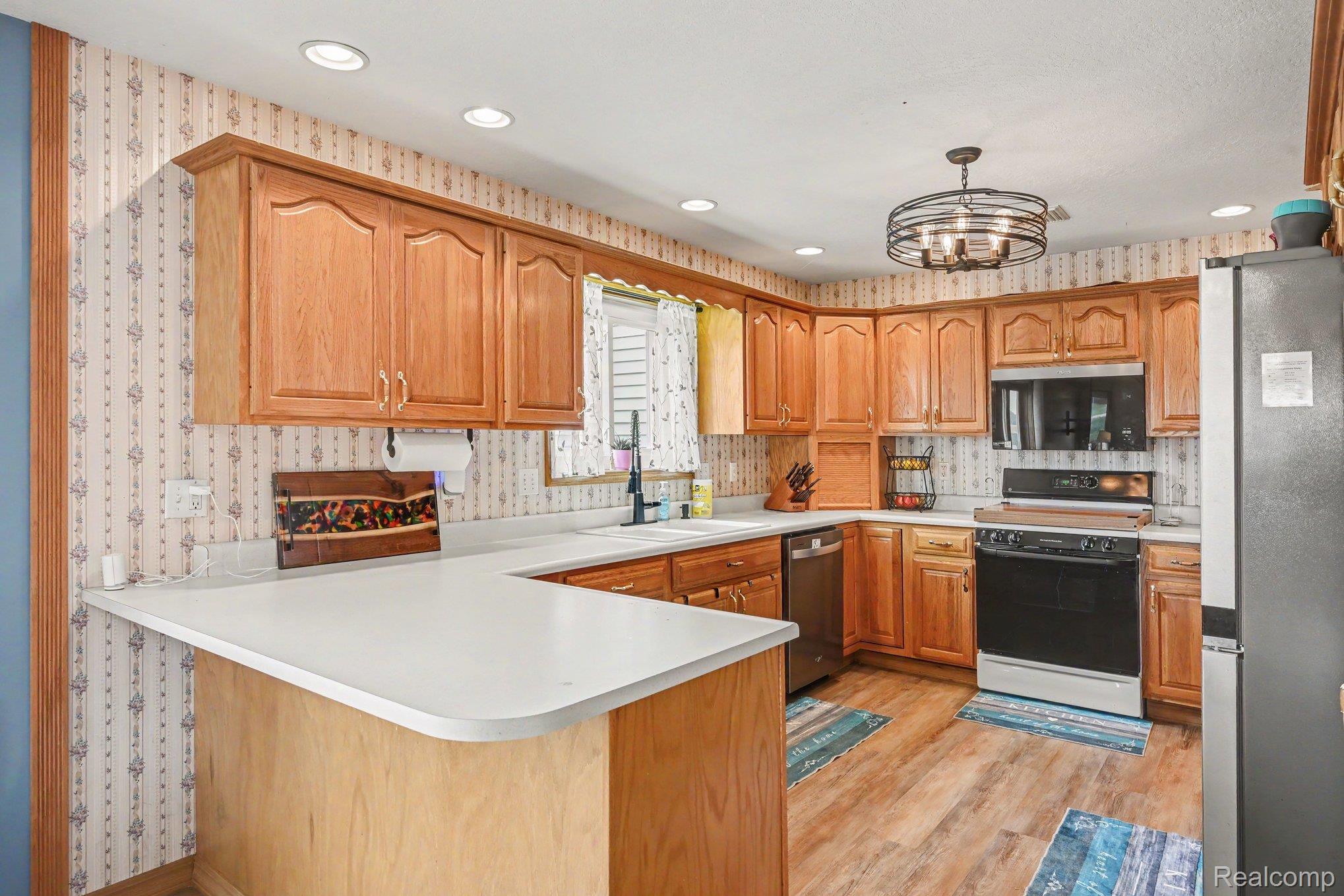 996 Arbogast Road Union City, MI 49094 - Photo 10 of 34 U-shaped kitchen featuring wood-finish cabinetry, solid surface countertops, and wood-finish flooring