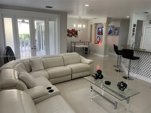 a kitchen with a refrigerator a stove a sink dishwasher a dining table and chairs with wooden floor