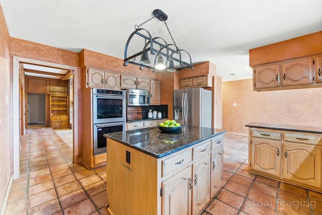 241 Simmons Road Double Oak, TX 75077 - Photo 12 of 40 Kitchen with stainless steel appliances, dark stone counters, a kitchen island, pendant lighting, and a textured ceiling