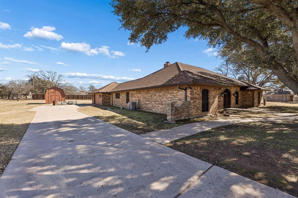 241 Simmons Road Double Oak, TX 75077 - Photo 4 of 40 View of home's exterior featuring a shed, a chimney, brick siding, driveway, and a lawn