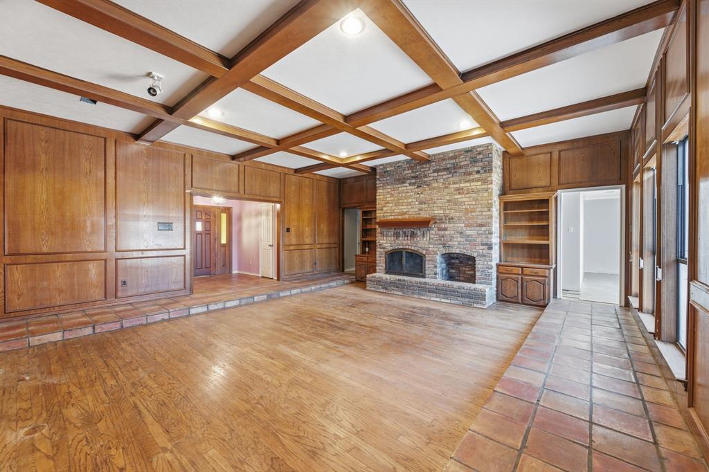 241 Simmons Road Double Oak, TX 75077 - Photo 10 of 40 Unfurnished living room with wooden walls, light wood-type flooring, coffered ceiling, a fireplace, and built in shelves