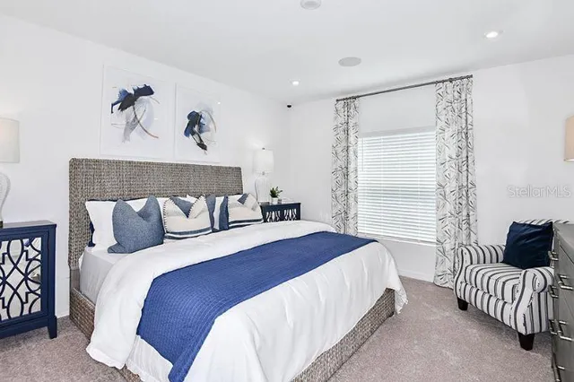 a bedroom with a bed and a lamp on dresser