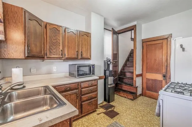 a kitchen with granite countertop a sink a stove and cabinets