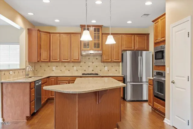 a kitchen with stainless steel appliances granite countertop a refrigerator and a stove top oven