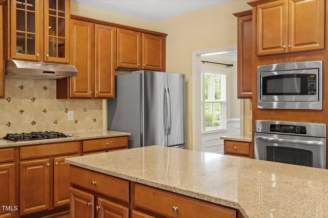 a kitchen with stainless steel appliances granite countertop a sink a stove and a wooden floors