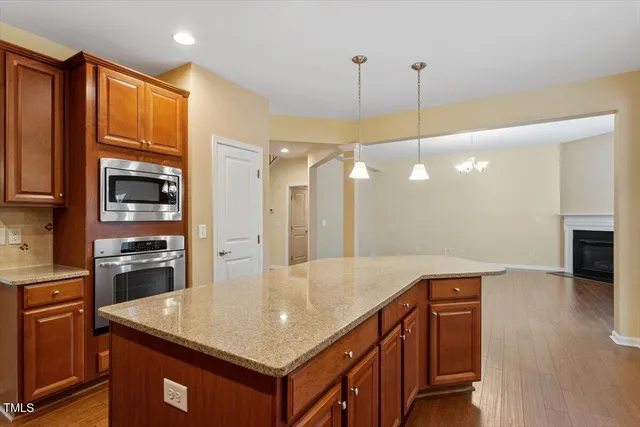 an empty room with wooden floor chandelier and fireplace