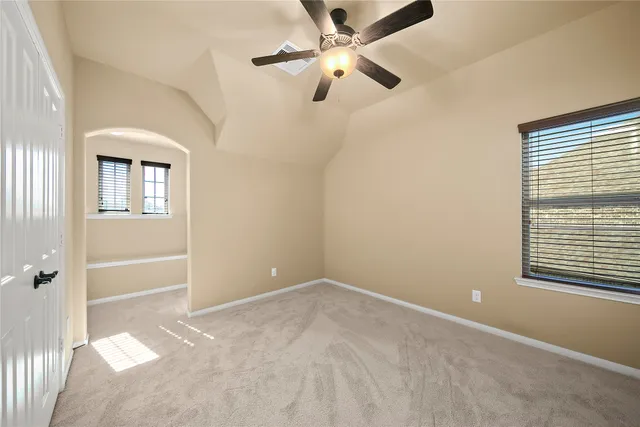 an empty room with chandelier fan and windows