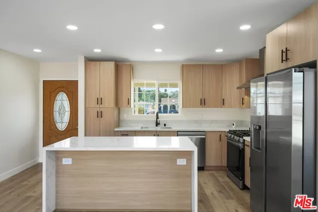 a kitchen with stainless steel appliances granite countertop a sink a stove and a refrigerator