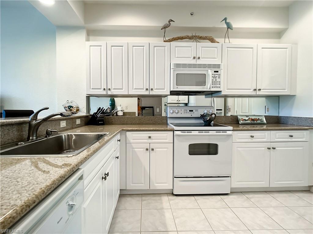 7930 Mahogany Run Lane, Unit 814 Naples, FL 34113 - Photo 12 of 29 a white kitchen with granite countertop white cabinets and white appliances