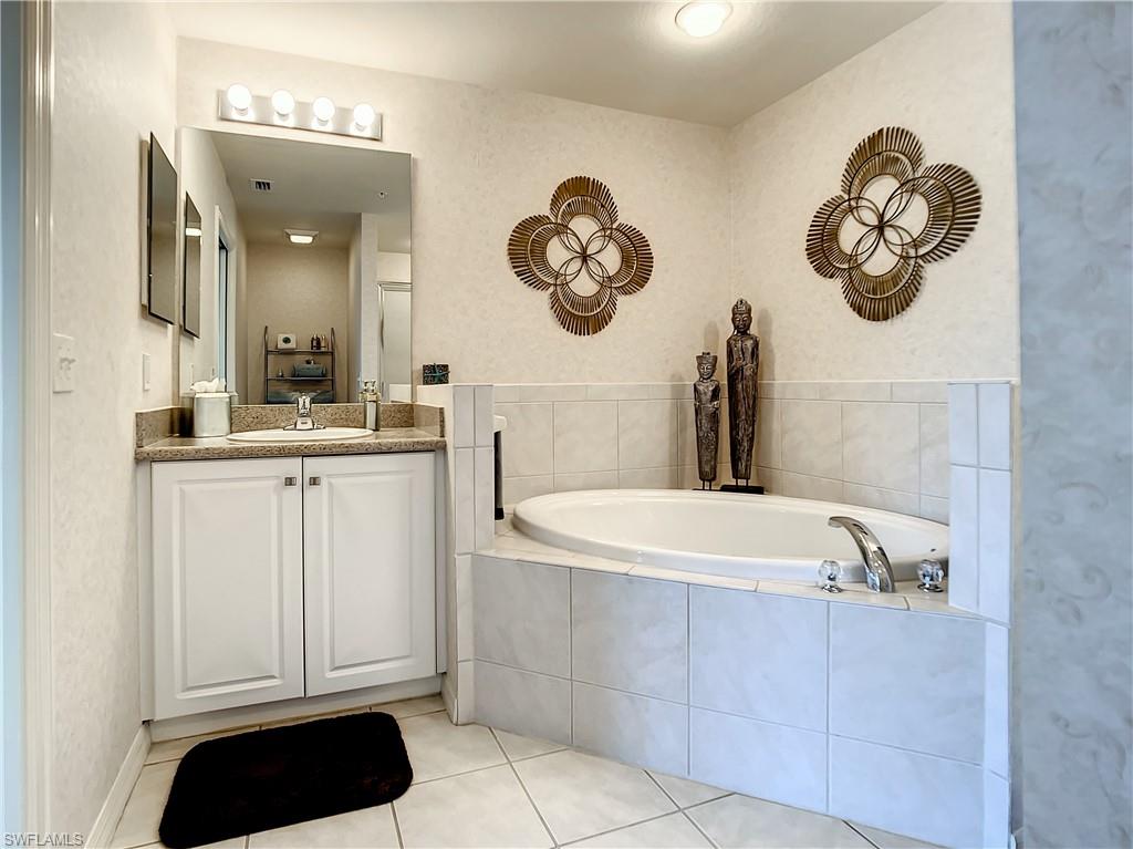 7930 Mahogany Run Lane, Unit 814 Naples, FL 34113 - Photo 20 of 29 a bathroom with a sink a bathtub and a mirror