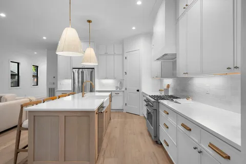 a kitchen with stainless steel appliances a stove a sink a center island and cabinets