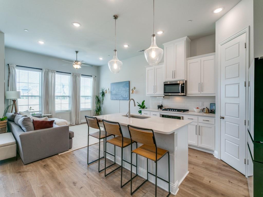 12964 Rockham Lane Dallas, TX 75234 - Photo 5 of 24 a large white kitchen with kitchen island granite countertop a stove a oven a couches and a dining table with wooden floor