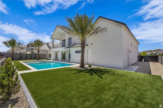 1620 Belayer Drive St. George, UT 84770 - Photo 43 of 51 Expansive backyard featuring a rectangular swimming pool with surrounding hardscaping, a manicured artificial turf lawn, and mature palm trees
