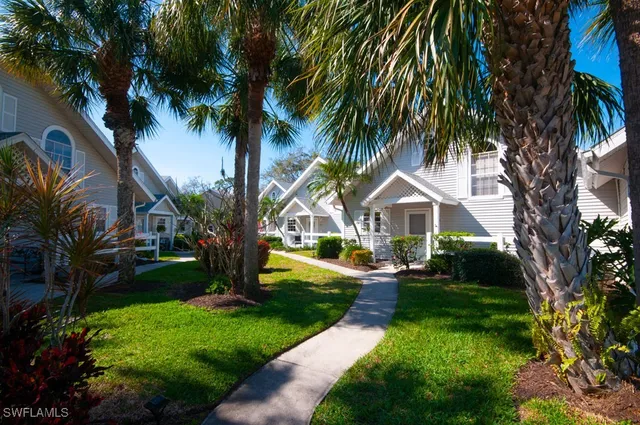a front view of a house with garden and trees