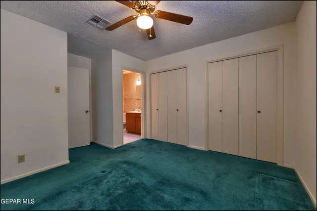 an empty room with closet and a chandelier fan