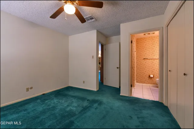 an empty room with closet and a chandelier fan