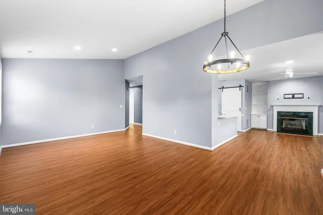 a view of empty room with wooden floor fireplace and window