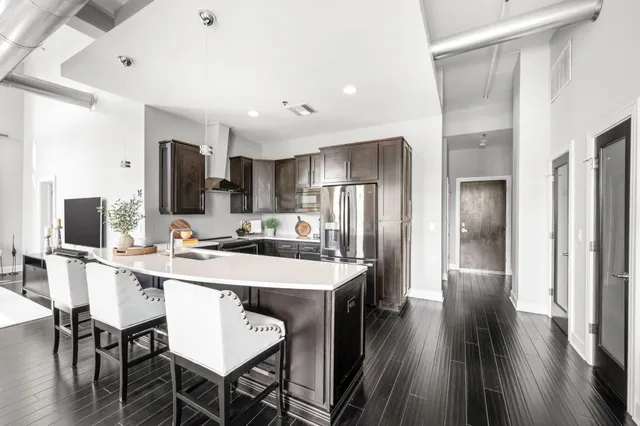 a large kitchen with stainless steel appliances sink a refrigerator and cabinets