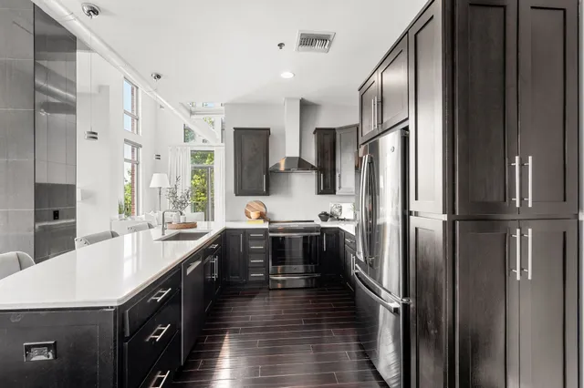a kitchen with stainless steel appliances kitchen island granite countertop a dining table chairs sink and cabinets