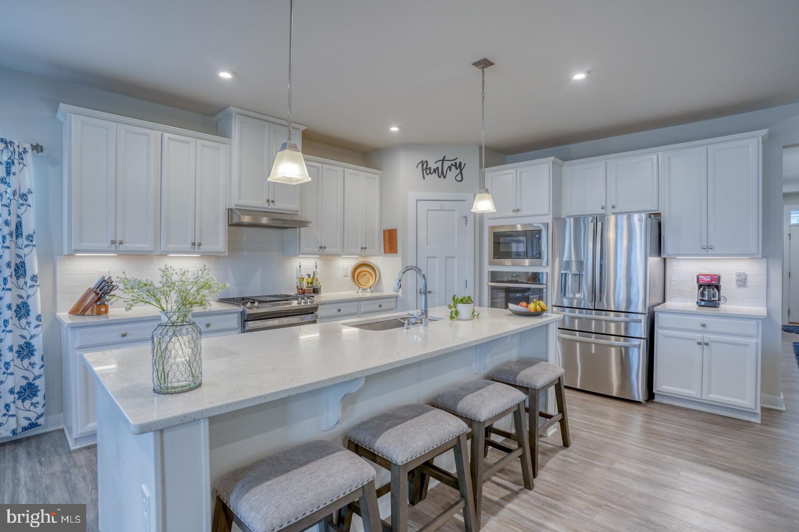 24077 Caldwell Circle Lewes, DE 19958 - Photo 16 of 60 a kitchen with refrigerator a stove a sink and chairs