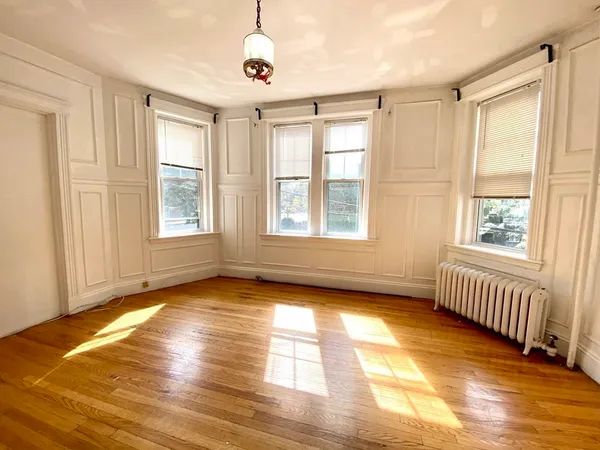 a view of an empty room with a window and wooden floor