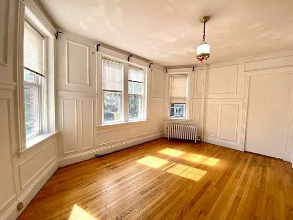 a view of an empty room with a window and wooden floor