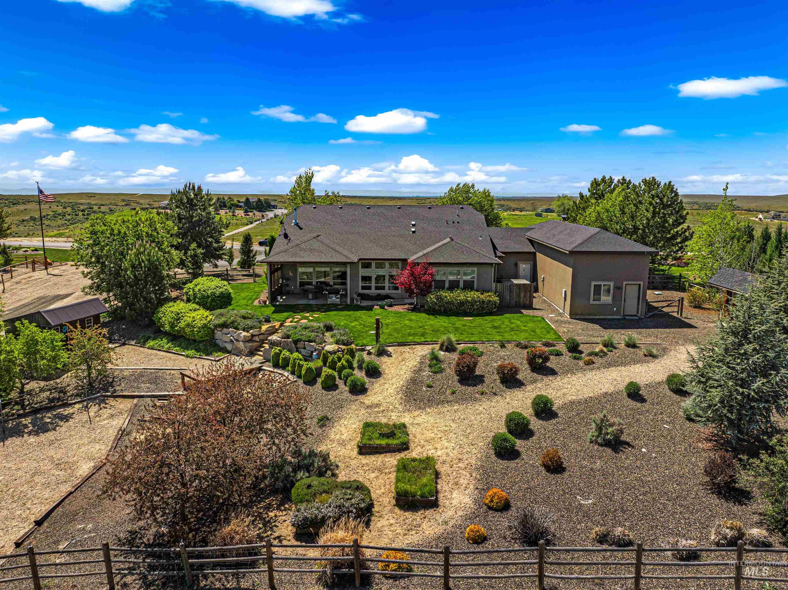 7521 North Grand Ridge Lane Eagle, ID 83616 - Photo 42 of 50 Expansive property featuring a large residence with an attached structure, a spacious patio, and a manicured lawn