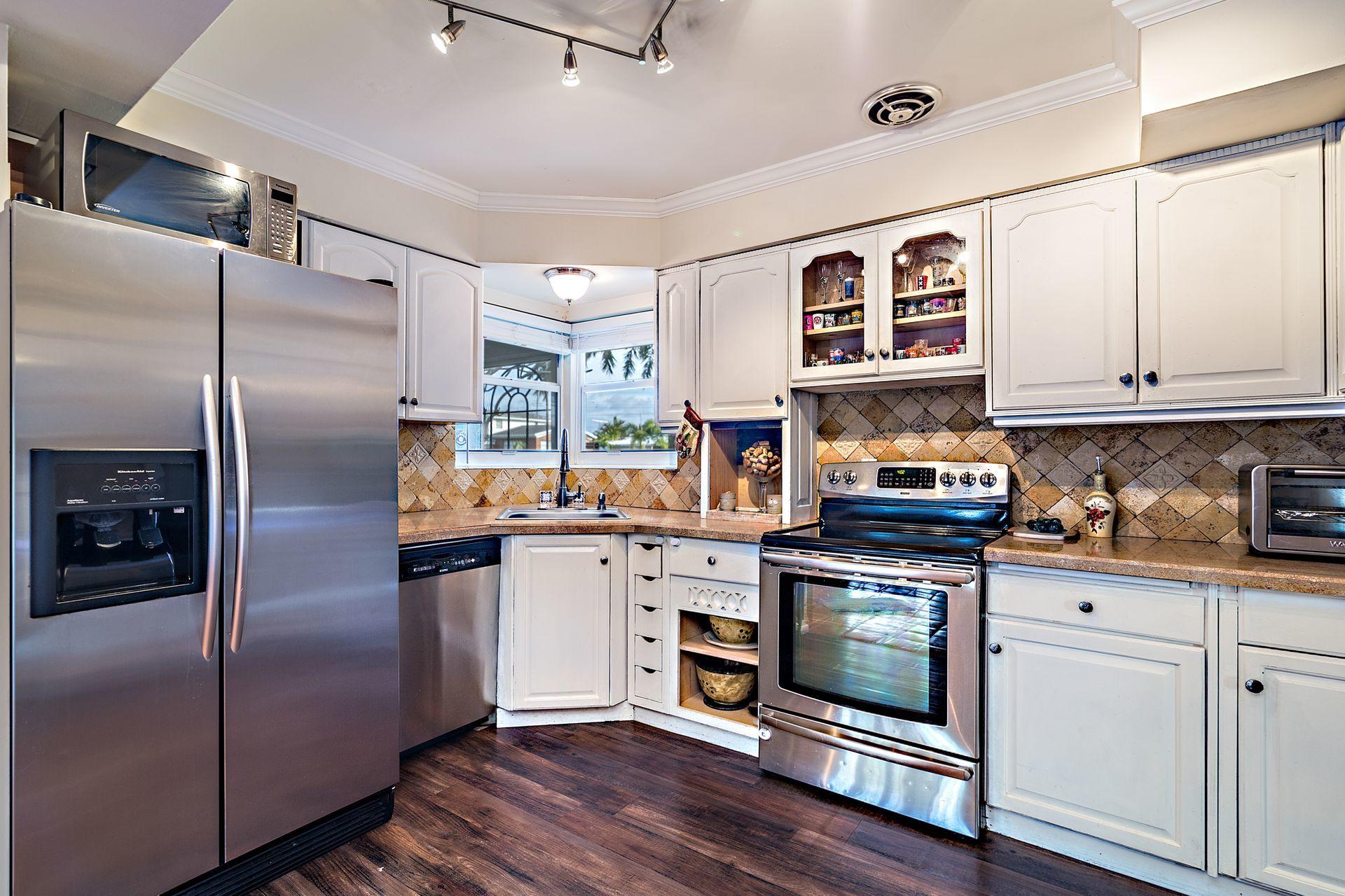 525 Inlet Road North Palm Beach, FL 33408 - Photo 8 of 26 a kitchen with stainless steel appliances granite countertop a refrigerator a stove and a sink with wooden floor
