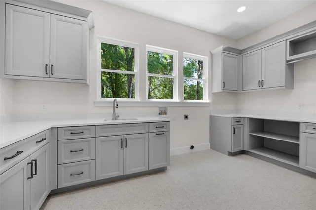 a kitchen with white cabinets and window