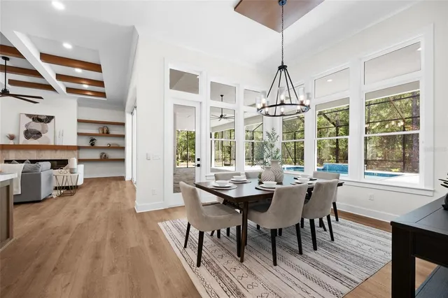 a dining room with stainless steel appliances granite countertop a table chairs and a wooden floor