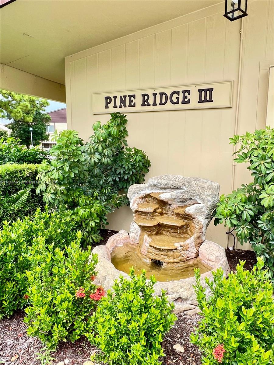 340 Pine Ridge Circle, Unit D1 Greenacres, FL 33463 - Photo 2 of 25 a view of a swimming pool with some plants and large trees