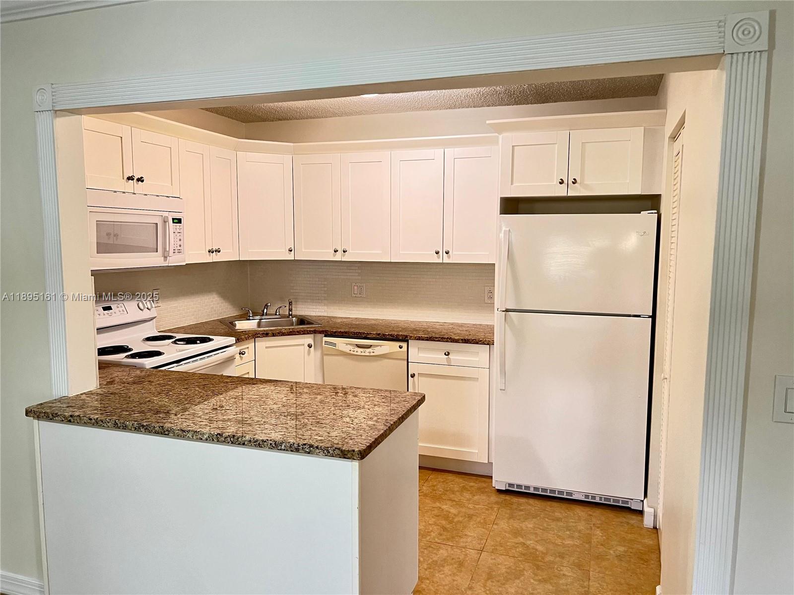340 Pine Ridge Circle, Unit D1 Greenacres, FL 33463 - Photo 6 of 25 a kitchen with granite countertop a refrigerator a stove a sink and a refrigerator