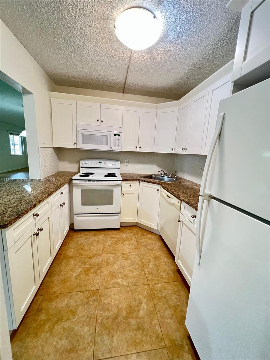 340 Pine Ridge Circle, Unit D1 Greenacres, FL 33463 - Photo 10 of 25 a white kitchen with cabinets appliances and a counter space