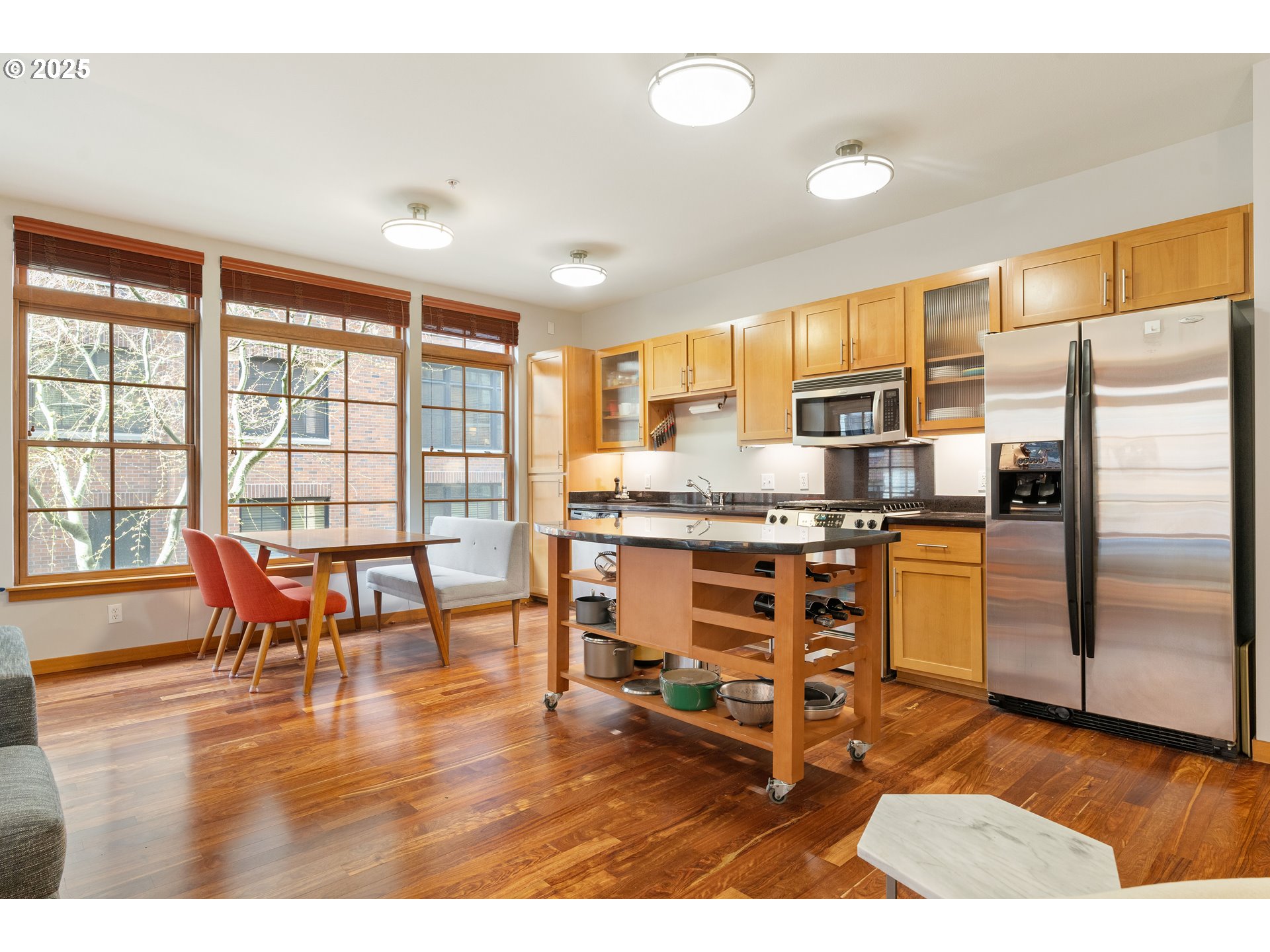 2350 Northwest Savier Street, Unit 202 Portland, OR 97210 - Photo 7 of 30 a kitchen with stainless steel appliances kitchen island granite countertop a refrigerator a stove a dining table and chairs with wooden floor