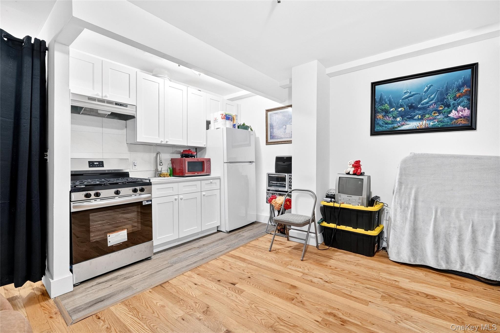 1459 Rosedale Avenue Bronx, NY 10460 - Photo 24 of 37 Kitchen with stainless steel gas range oven, white cabinetry, under cabinet range hood, freestanding refrigerator, and light wood-style floors