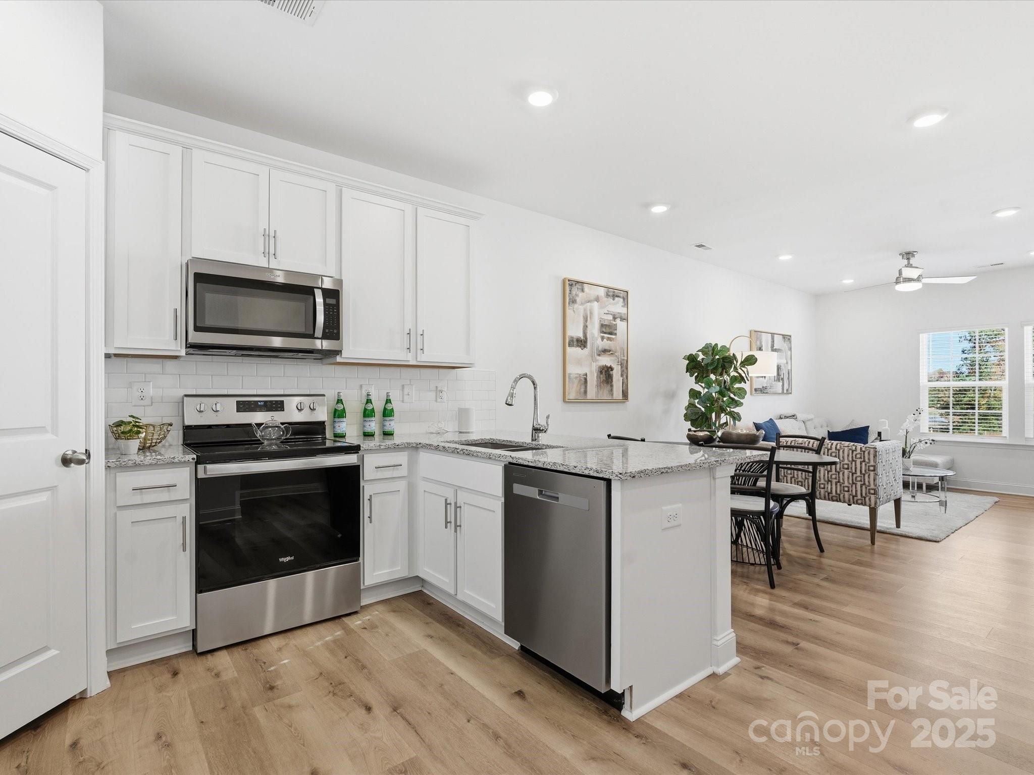 3132 Butler Hl Drive Matthews, NC 28105 - Photo 13 of 36 a kitchen with stainless steel appliances kitchen island granite countertop a stove top oven a sink a dining table and chairs