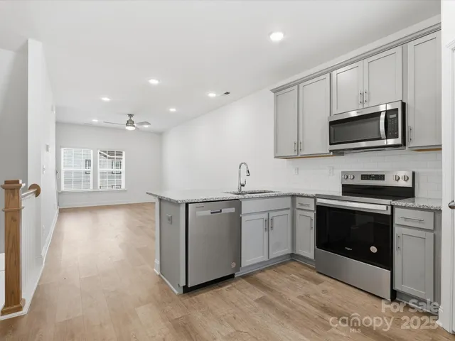 a kitchen with stainless steel appliances granite countertop a stove a sink and a microwave