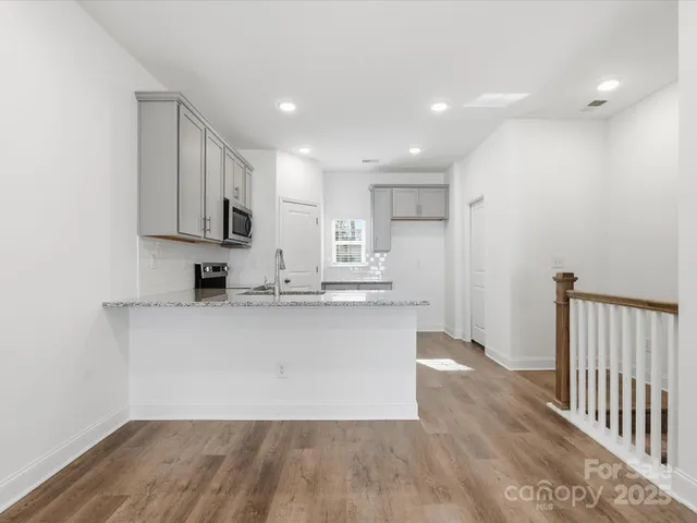 a view of kitchen with stainless steel appliances granite countertop cabinets and wooden floor