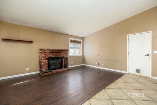 613 South Silver Ridge Street Ridgecrest, CA 93555 - Photo 14 of 26 an empty room with wooden floor fireplace and windows
