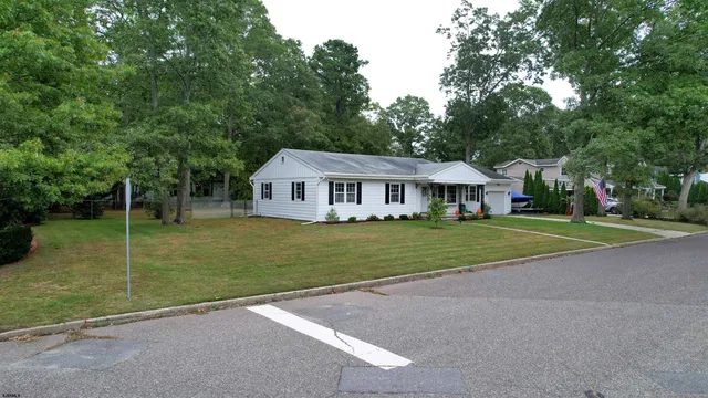 a view of house with a big yard and large trees